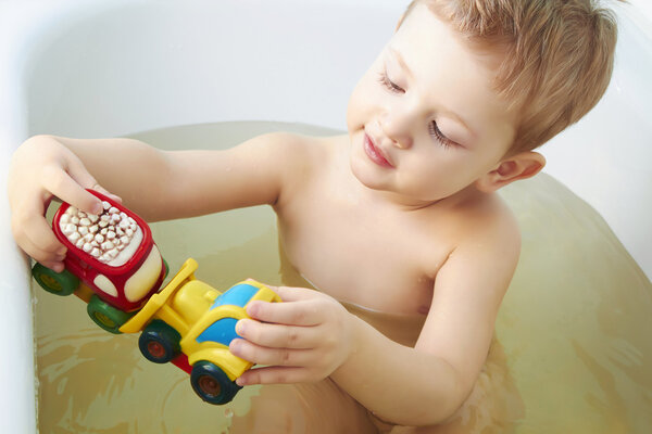 little boy plays toys in bathroom