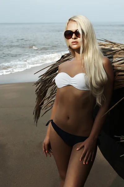 Hermosa mujer rubia en una playa con barco — Foto de Stock