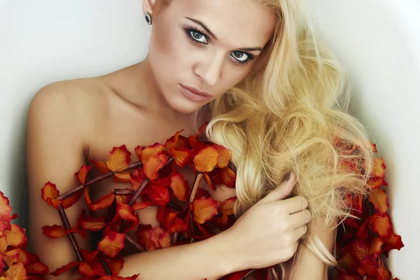 Mooie sexy blonde vrouw in een bad met oranje bloemen — Stockfoto
