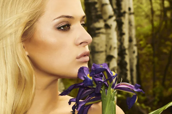 Hermosa mujer rubia con flores azules en un bosque —  Fotos de Stock