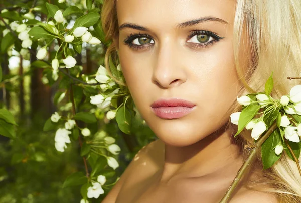 Beautiful blond woman in green forest. flowers — Stock Photo, Image