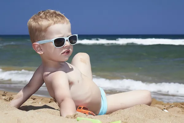 Dítě sedí na pláži v písku. malý chlapec v blízkosti moře — Stock fotografie
