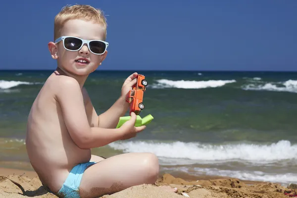 Niño en gafas de sol en la playa. niño pequeño cerca del mar — Foto de Stock