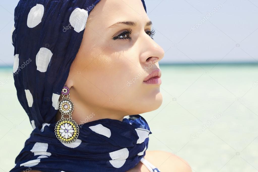 Beautiful woman in a blue scarf on the beach