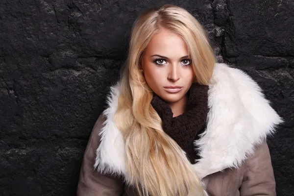 Bella donna bionda in pelliccia vicino al muro di mattoni. inverno — Foto Stock