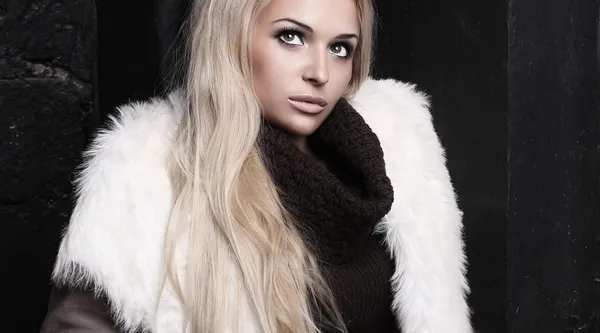 Belle femme blonde en fourrure près du mur de briques. mode d'hiver. manteau de fourrure. le maquillage — Photo