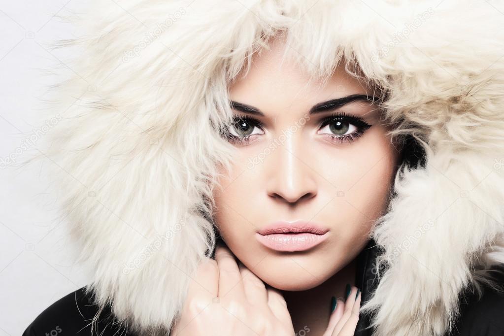 Fashion portrait of young beautiful woman with fur. white fur hood. winter style.