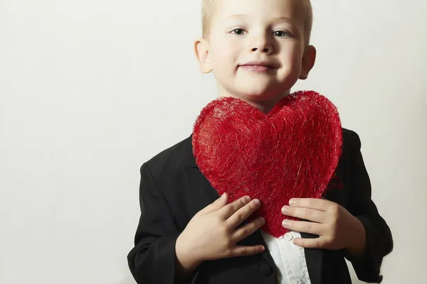 赤いハートを持つ子供の笑みを浮かべてください。ハート記号と 4 歳の男の子。黒の素敵な子供に合わせてバレンタインの日 — ストック写真