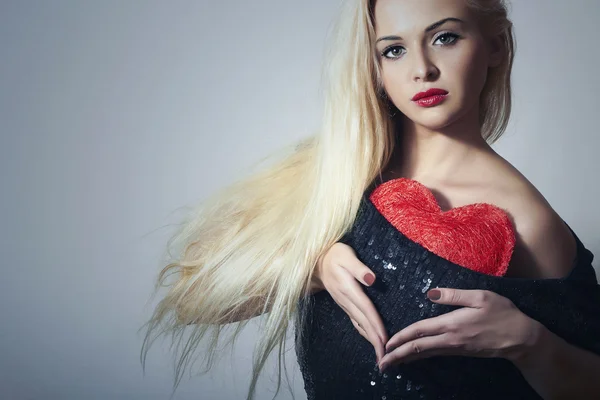 Hermosa mujer rubia con corazón rojo. Chica Belleza. Muestra el símbolo del amor. Día de San Valentín. Vestido negro — Foto de Stock