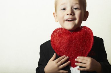 Kırmızı kalpli çocuk gülümsüyor. komik çocuk kalp simgesi olan. güzel çocuk siyah takım elbise Sevgililer günü anne için