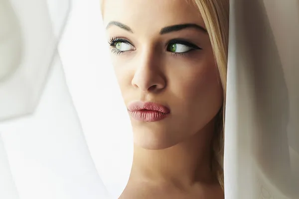 Hermosa cara de joven rubia novia. Mirada de chica en ventana. Velo nupcial. Cortinas — Foto de Stock