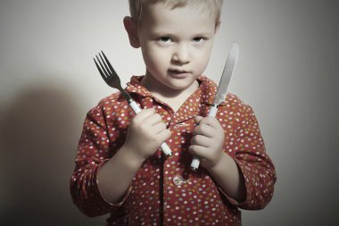 kleiner hübscher Junge mit Gabel und Messer. hungriges Kind. Schönheit und Essen. essen wollen