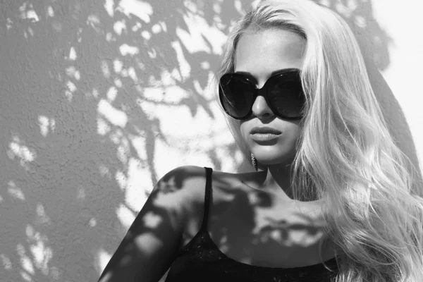 Svartvita porträtt av vacker kvinna i sunglasses.shadows på den face.blond flickan nära väggen — Stockfoto