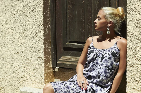 Beautiful blond woman near old wooden door.beauty girl in colored dress.old house.summer — Stock Photo, Image