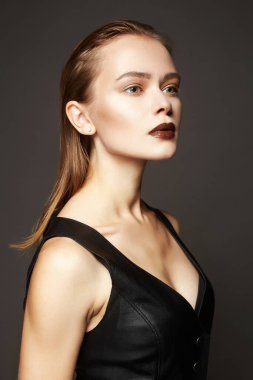 Deri elbiseli, şehvetli, genç bir kadın. Islak saçlı güzel bir makyajcı kız.