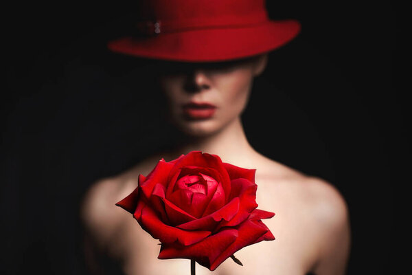 Silhouette of beautiful woman in hat behind a red rose. Lovely girl with make-up and Flowerportrait