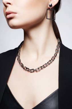 Zincirli kolyesi olan güzel bir kadın. Deri elbiseli kızda şık mücevherler.