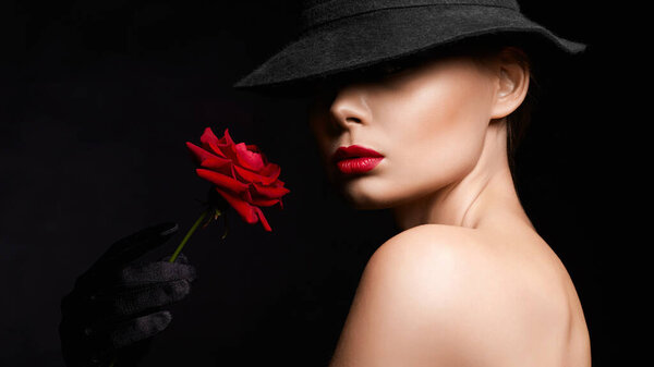 Beautiful young Woman In Hat and Gloves holding Flower. Lovely girl with make-up and Red Rose. beauty portrait