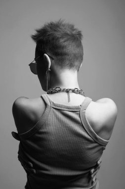Female back. Young beautiful woman with short hair and a chain necklace in glasses