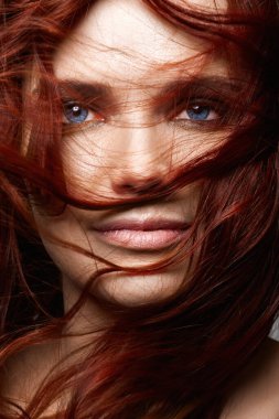 Kıvırcık kızıl saçlı ve mavi gözlü güzel bir genç kadın. Sağlıklı saçlı kızın güzel yakın plan portresi.