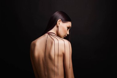 Sırtında kolyesi olan genç ve güzel bir kadın. Mücevherleri olan çıplak kız