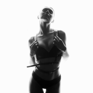 black and white portrait of Beautiful woman in leather belt and underwear. sexy girl iin white lights