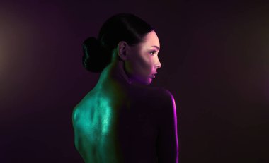 Kadın sırtı. Renkli ışıklar içinde güzel bir genç kadın. Güzel, çıplak, parlak vücutlu kız.