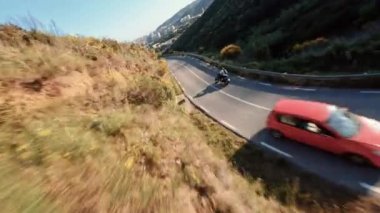Fast motorcycle riding on serpentine road during golden hour, driver with white long sleeve shirt . followed with high speed fpv drone, 4k footage