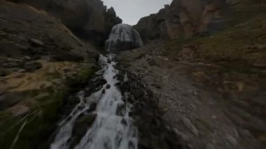 Fast FPV drone shot up along the mountain dew towards to the big waterfall. High quality 4k footage