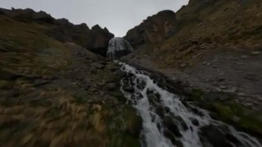 Fast FPV drone shot up along the mountain dew towards to the big waterfall. High quality 4k footage