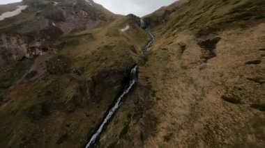 Fast FPV drone shot up along the mountain dew towards to the big waterfall. High quality 4k footage