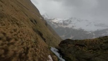 Drone shot down a waterfall, along the mountain dew towards to beautiful valley . High quality 4k footage