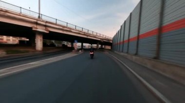 Hızlı gri BMW motosikleti, yüksek hızda FPV İHA ile çekilen inşaat altında şehir yoluna çıkıyor. Sabahın erken saatlerinde tamamen siyah giyinmiş bir sürücü. Yüksek kalite 4k görüntü