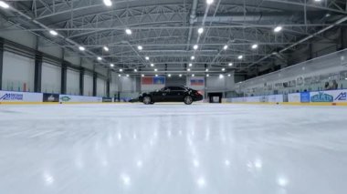 FPV İHA 'sı, buz hokeyi sahasında siyah arabanın altında diğer İHA' larla yan yana kayıyor. Hava Aracı Yüksek Açı İzleme Çekimi. Yüksek kalite 4k görüntü