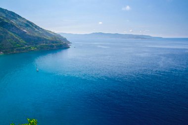 Yeşil tepenin ve sahil kasabası Scilla 'nın limanı, Tyrhenian körfezi kıyısı, Sicilya adası ve mavi gökyüzünün suluboya çizimi, Calabria, Güney İtalya