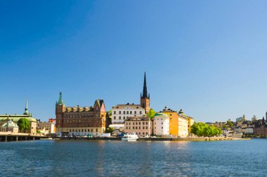 Riddarholmen ada bölgesinin suluboya çizimi. Riddarholm Kilisesi kuleleri ve tipik renkli gotik binalar. Kungsholmen, Stockholm 'den Malaren Gölü' ne demirlemiş gemi.