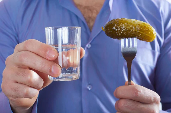 Man with a glass of vodka and a cucumber on a fork in his hand — Stock Photo, Image