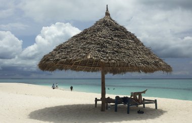 kadın ve adam ahşap şemsiyesi altında sahilde rahatlatıcı