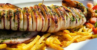 Tabakta servis edilen salata ve patates kızartmasıyla kızartılmış kalamar.