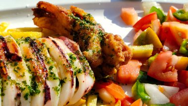 Tabakta servis edilen salata ve patates kızartmasıyla kızartılmış kalamar.