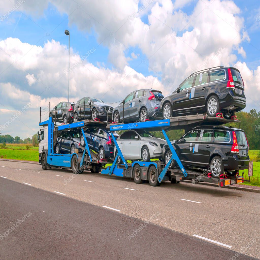 AMSTERDAM, HOLLAND-SEPTEMBER 2014. Truck trailer carrying several cars on a highway.