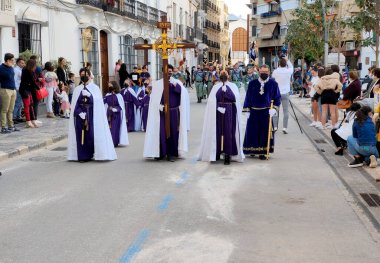 COIN SPAIN - APRIL 2022. Tourist walking in the Catholic procesion of holy week in a sunny day. 