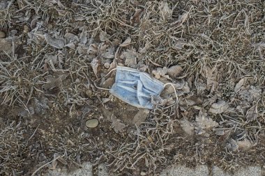 Covid-19 salgını sırasında donmuş çimlerde yatan bir cerrahi maske.