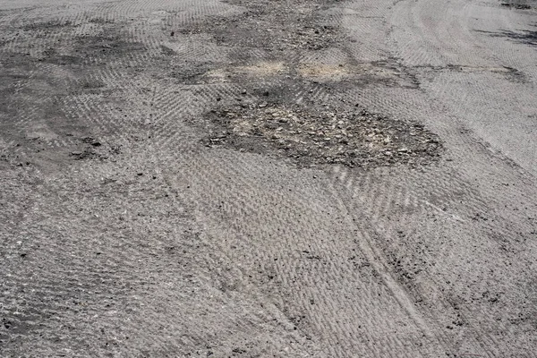 Onarım sürecinde değirmenli yüzeyi olan hasarlı bir yol.