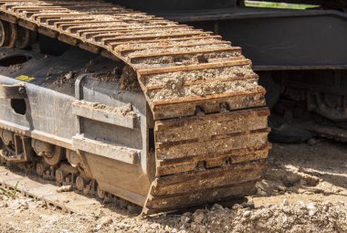 the continous track of an earth mover filled with soil at a construction site