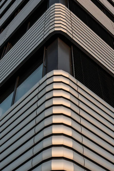 the metal covered corner of an office building in evening sunlight
