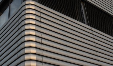 Akşam güneşi bir ofis binasının metal cephesinde parlıyor.