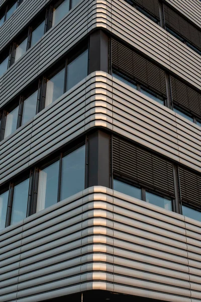 an office building with a metal covered facade in evening sunlight with lowered blinds