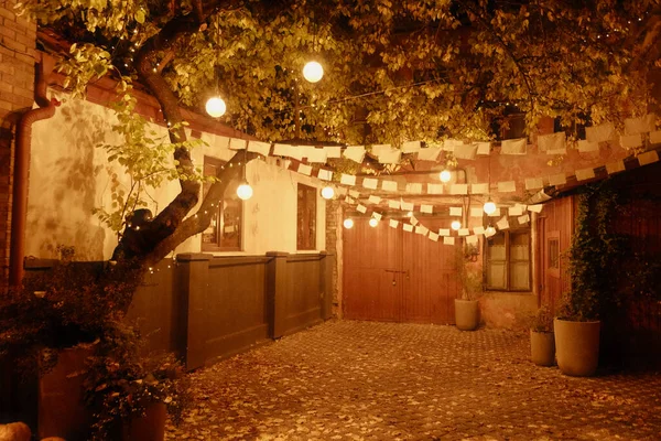 Halloween night. Beautiful courtyard with wooden tables and chairs near the cafe at Halloween night. Neat yard with wood, light wood tables and chairs in the yard.