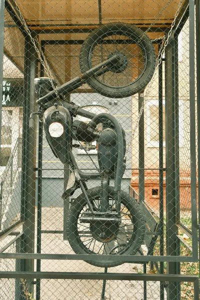 Sculpture of a motorcycle standing on the rear wheel. Metal sculpture of a motorcycle in an iron grid